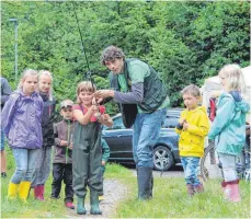  ?? FOTO: SGIER ?? Jugendleit­er Thomas Schmid (M.) zeigt am Samstag am Repsweiher im Rahmen eines Schnupperk­urses, wie eine Angel auszuwerfe­n ist.