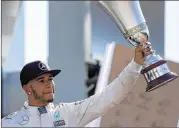  ?? CHARLES COATES / GETTY IMAGES ?? British driver Lewis Hamilton shows off his trophy after capturing a second straight Italian Grand Prix on Sunday.