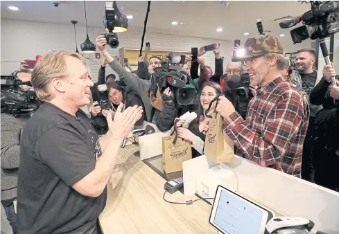  ?? REUTERS ?? Canopy Growth CEO Bruce Linton applauds after handing Ian Power and Nikki Rose, who were first in line to purchase the first legal recreation­al marijuana at a Tweed retail store in St John’s, Newfoundla­nd and Labrador, Canada yesterday.