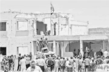  ??  ?? Syrian security forces raise the government flag in the main square of the town of Rastan in the central Homs province.— AFP photo