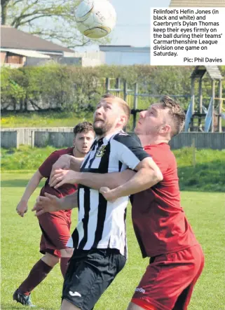  ?? Pic: Phil Davies ?? Felinfoel’s Hefin Jones (in black and white) and Caerbryn’s Dylan Thomas keep their eyes firmly on the ball during their teams’ Carmarthen­shire League division one game on Saturday.