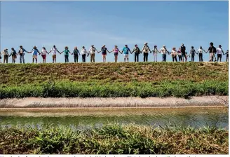  ?? / AMERICAN-STATESMAN PHOTOS BY TAMIR KALIFA ?? Hundreds of people who oppose plans to build a border wall join hands along the levee that passes through the Santa Ana Wildlife Refuge, a biological­ly diverse area that is home to hundreds of bird and butterfly species. See more photos and a video...