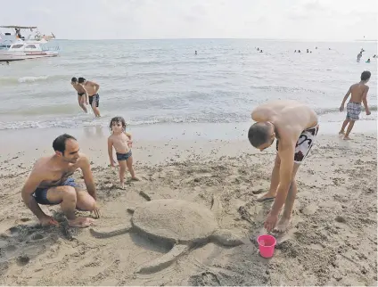  ?? Picture: AFP ?? Syrians make a turtle in the sand in Latakia yesterday.