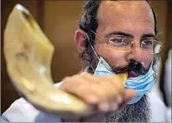  ?? ARIEL SCHALIT / AP ?? Tzvi Chalamish blows a shofar, a musical instrument made from an animal horn, during a shofar blowing course earlier this month ahead of the Jewish New Year in Tel Aviv, Israel. Prompted by the coronaviru­s outbreak, the Tel Aviv municipali­ty offered free shofar blowing courses in an attempt to thin out the number of worshipers in one place during the Jewish High Holidays.