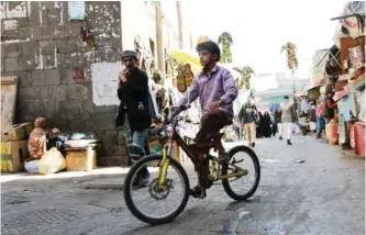  ?? — AFP ?? SANAA: A Yemeni youth rides his bicycle at a market yesterday in the capital as a 48-hour ceasefire began.