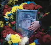  ?? DANIEL COLE/AP ?? Anna Korostensk­a touches a picture of her late fiancee, Oleksii, Jan. 23 at his grave in Bucha.