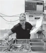  ?? ?? Jerry Tillman, a longtime employee, dishes up to-go orders in the kitchen.