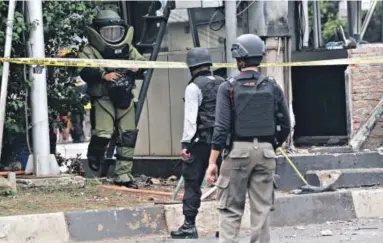  ??  ?? Members of a police bomb squad inspect a police post where an explosion went off in Jakarta, Indonesia, on Thursday. Attackers affiliated with the Islamic State terrorist group set off explosions at a Starbucks cafe in a bustling shopping area in the...