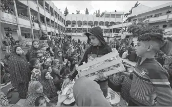  ?? MOHAMMED ABED / AFP ?? A boy distribute­s sweets to displaced Palestinia­ns as they attend a morning prayer to start the Eid al-Fitr festival, marking the end of the holy month of Ramadan in Rafah on Wednesday.