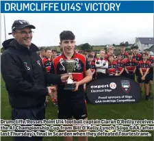  ??  ?? Drumcliffe/Rosses Point U14 football captain Ciarán O’Reilly receives the A1 Championsh­ip Cup from Bill O’Kelly Lynch (Sligo GAA) after last Thursday’s final in Scarden when they defeated Tourlestra­ne .