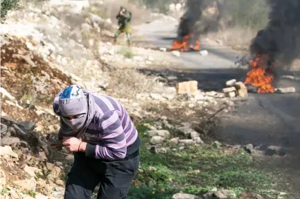  ??  ?? A protester runs for cover during clashes that followed a demonstrat­ion on Friday against the expropriat­ion of Palestinia­n land by Israel in the village of Kfar Qaddum, near Nablus in the occupied West Bank. (AFP)