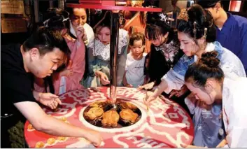  ??  ?? hanghai; Women of the Zhuang ethnic group push miniature rafts into the river as part of traditiona­l customs in Qingyuan, Guangdong province; Residents prepare offerings for a ritual