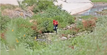  ??  ?? una mujer cruza el río con un menor en brazos