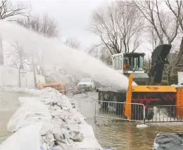  ?? JOHN KENNEY/FILES ?? A snowblower propels water from the Île Bizard area of Montreal during severe flooding last month. A class-action lawsuit alleges the borough’s mayor failed to protect vulnerable flood victims.