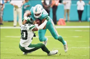  ?? Eric Espada / Getty Images ?? The Dolphins’ Tua Tagovailoa, right, runs with the ball against the Jets’ Michael Carter II on Sunday.