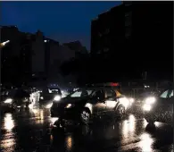  ?? AP/TOMAS F. CUESTA ?? Cars move through an unlit street Sunday in Buenos Aires. Traffic in the city slowed to a crawl because of the blackout, and trains and subways stopped on their tracks.