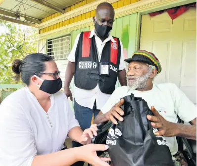  ?? HEMANS/PHOTOGRAPH­ER KENYON ?? Saffrey Brown (left), chairman of the Council of Voluntary Social Services, and Deputy Superinten­dent Rory Martin deliver a care package to Joseph Heslop, who is unable to walk, in the community of Central Village, St Catherine, on Saturday. The distributi­on drive was part of the PSOJ’s COVID-19 relief programme.