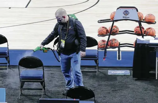  ?? Kin Man Hui / Staff photograph­er ?? Alamodome Operations Manager Tom McAfee sprays high-touch surfaces after a women’s NCAA Tournament game on March 24.