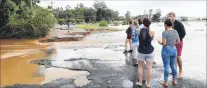  ??  ?? Residents inspect where floodwater­s destroyed the main road in South Murwillumb­ah, New South Wales.