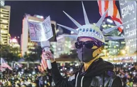  ?? Marcus Yam Los Angeles Times ?? PRO-DEMOCRACY demonstrat­ors celebrate Thursday in Hong Kong’s Central district after President Trump signed two bills in support of their human rights.