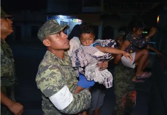  ??  ?? Soldiers help children to get on a truck as residents are evacuated from their coastal town after an earthquake struck off the southern coast, in Puerto Madero, Mexico. Photo: Jose Torres