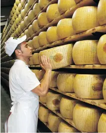  ?? BLOOMBERG ?? A worker selects a whole Parmigiano-Reggiano cheese from a rack ahead of inspection at Coduro cheesemake­rs in Fidenza, Italy.