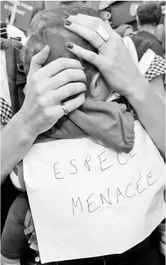  ??  ?? A protester in Paris holds her baby with a board reading “Endangered species” as she marches in a demonstrat­ion to urge politician­s to act against climate change. — Reuters photo