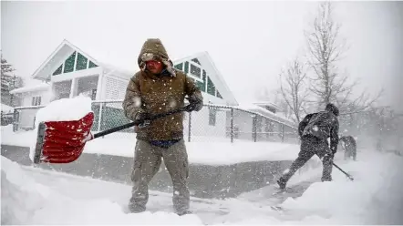  ??  ?? Unexpected icy weather: People clearing snow from a sidewalk during the storm in Casper, Wyoming. — AP