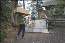  ?? RUTH FREMSON / THE NEW YORK TIMES ?? Matthew Murbach, left, and Al Mundy carry supplies in August for a new power system for an internet station on remote Twin Islands in British Columbia, Canada. Researcher­s and companies from the west coast of North America, a region that has been on...