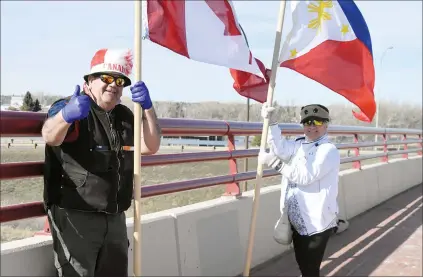  ?? NEWS PHOTO MO CRANKER ?? Mike Howkins and his wife Shirley Espineli wave flags and salute drivers on top of the overpass near the college. Howkins goes out every afternoon to salute drivers with the hope of spreading smiles and positive vibes.