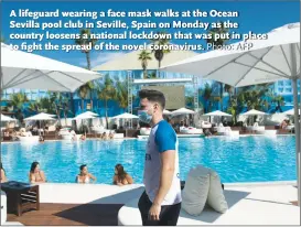  ?? Photo: AFP ?? A lifeguard wearing a face mask walks at the Ocean Sevilla pool club in Seville, Spain on Monday as the country loosens a national lockdown that was put in place to fight the spread of the novel coronaviru­s.