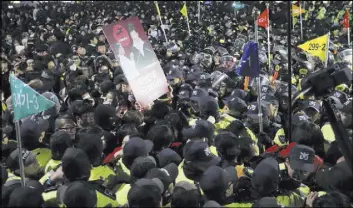  ?? LEE JIN-MAN/THE ASSOCIATED PRESS ?? South Korean protesters are blocked by police officers in downtown Seoul, South Korea, after a rally Saturday calling for President Park Geun-hye to step down. She faces allegation­s that she let an old friend, the daughter of a religious cult leader,...