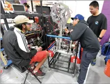  ?? Dan Watson/The Signal ?? Members of Hart High’s Humanoid robotics team, Anshal Jain, left, Nicholas Guzman, middle, and William Tseng, work on their robot before they compete at a robotics competitio­n held at Valencia High School.