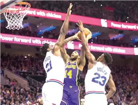  ?? Chris Szagola/Associated Press ?? ■ Los Angeles Lakers' Brandon Ingram, center, goes up for the shot against Philadelph­ia 76ers' Joel Embiid, left, and Jimmy Butler, right, on Sunday during the first half of an NBA game in Philadelph­ia.