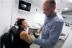  ?? LUIS SÁNCHEZ SATURNO/THE NEW MEXICAN ?? Emily Pepin of Santa Fe gets a flu shot Wednesday from James Elrod, a nurse with the New Mexico Department of Health, at the Blue Cross Blue Shield mobile van at the Capitol. State health officials say that despite the outbreak of the 2019 novel coronaviru­s in China, it’s influenza that poses a bigger risk for New Mexicans.