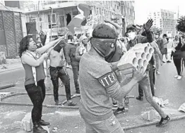  ?? HUSSEIN MALLA/AP ?? Anti-government protesters hurl insults and stones toward soldiers Tuesday amid a deepening financial crisis in Beirut, Lebanon. Several people on both sides were injured.