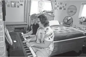  ?? KYLE ROBERTSON/COLUMBUS DISPATCH ?? Philip Baltzer, in the forefront, and his boyfriend Nick Mayes play the piano in the bedroom of their South Side home. Both Baltzer and Mayes are music teachers. Baltzer, 24, said he recently realized he’d been through conversion therapy by a local pastor after watching the Netflix documentar­y “Pray Away.”