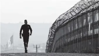  ?? ASSOCIATED PRESS FILE PHOTO ?? Border Patrol agent Eduardo Olmos walks near the secondary fence separating Tijuana, Mexico, background, and San Diego recently. California has rejected the federal government’s initial plans to sends National Guard troops to the border because the...