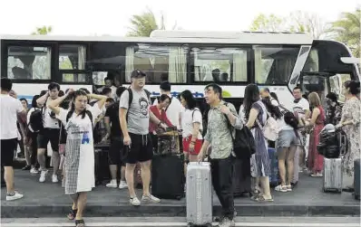  ?? Tingshu Wang / Reuters ?? Turistas bajan de un autobús en un hotel en Sanya, en la provincia china de Hainan, en una imagen de 2020.