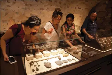  ?? Associated Press ?? ■ Visitors look at an exhibit titled “The House of Herod: Life and Power in the Age of the New Testament,” June 27 at the Terra Sancta Museum in the Old City of Jerusalem. Jerusalem’s Franciscan friars have opened the museum, which is filled with artifacts from biblical sites relating to daily life in Jesus’ time.
