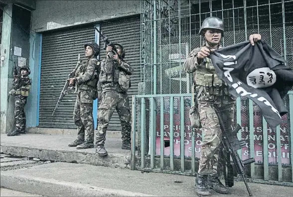  ?? JES AZNAR / GETTY ?? La bandera negra. Un soldado filipino observa una bandera del Estado Islámico capturada a los militantes yihadistas en la ciudad de Marawi, en la isla de Mindanao, donde el ejército combate al grupo radical Maute