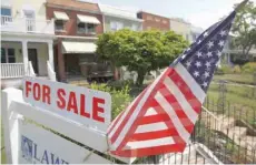  ?? — AFP ?? A US flag decorates a house for-sale sign in Capitol Hill, Washington.