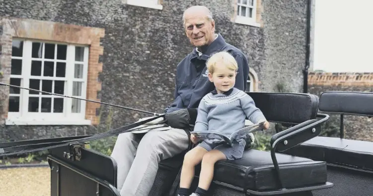  ??  ?? 0 Two-year-old Prince George sits by his great-grandfathe­r Philip's side on the box seat of a carriage, holding a book, as the duke holds the reins and a whip