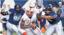  ?? ELI LUCERO/THE HERALD JOURNAL VIA ASSOCIATED PRESS ?? New Mexico quarterbac­k Sheriron Jones (4) runs with the ball as Utah State’s Christophe­r Unga (96) and defensive end Fua Leilua (44) defend during the Aggies’ 61-19 victory on Saturday.