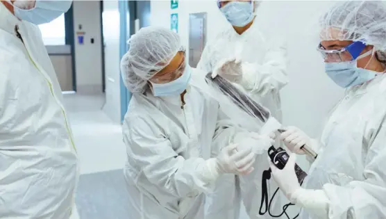  ?? | ERIC KAYNE FOR KHN ?? After suiting up in three layers of scrubs, staff at Bayer’s factory in Berkeley, California, help reporter Jenny Gold wrap her microphone in a hairnet to maintain a sterile environmen­t for manufactur­ing factor VIII.