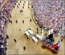  ?? Rick Steves’ Europe/RICK STEVES ?? The crowd looks on as an oxen cart pulls the Palio banner through Siena’s main square.