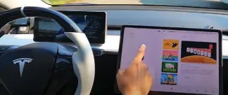  ?? ?? Distractio­n: A Tesla driver chooses a video game on the console