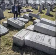  ?? MICHAEL BRYANT — THE PHILADELPH­IA INQUIRER VIA AP ?? Northeast Philadelph­ia Police Det. Timothy McIntyre and another Philadelph­ia police officer look over tombstones that were vandalized in the Jewish Mount Carmel Cemetary Sunday in Philadelph­ia. A police spokeswoma­n said preliminar­y estimates are that...