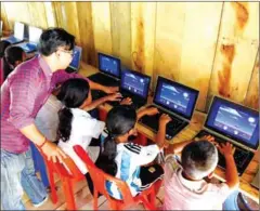  ?? AFP ?? A teacher tending to students learning the use of computers at the Coconut School at Kirirom national park in Kampong Speu province.