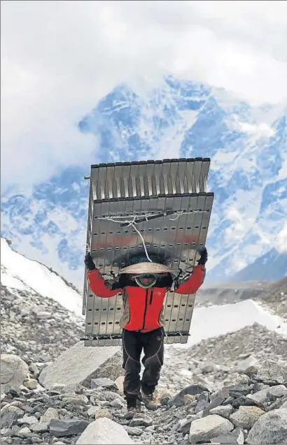  ?? TASHI SHERPA / AP ?? Un porteador cargando, el pasado marzo, escaleras que se han colocado en la Cascada de Hielo